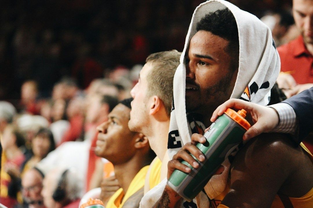 Basketspelare med handduk över huvudet dricker ur en sportflaska
