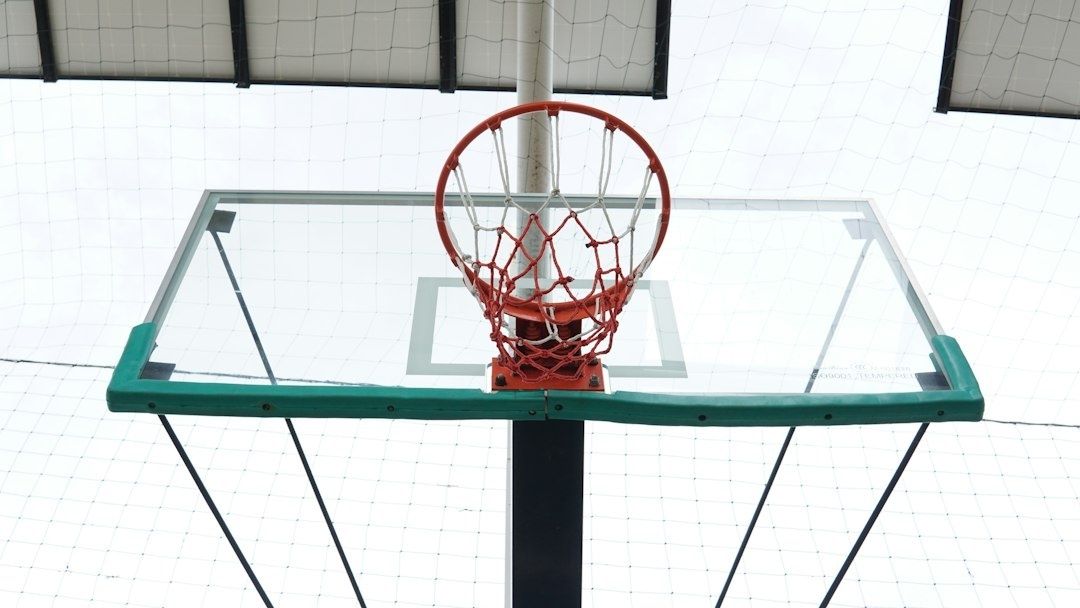 Närbild av basketkorg och genomskinlig planka i en idrottshall